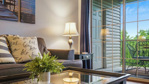 Ein stilvolles Wohnzimmer mit einer Couch, einem Couchtisch, einer Lampe und einer Topfpflanze.
