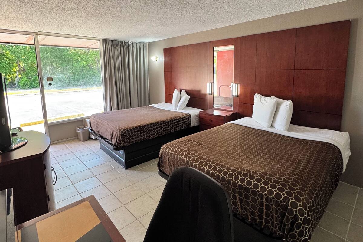 Habitación de hotel con dos camas, un escritorio y una silla.