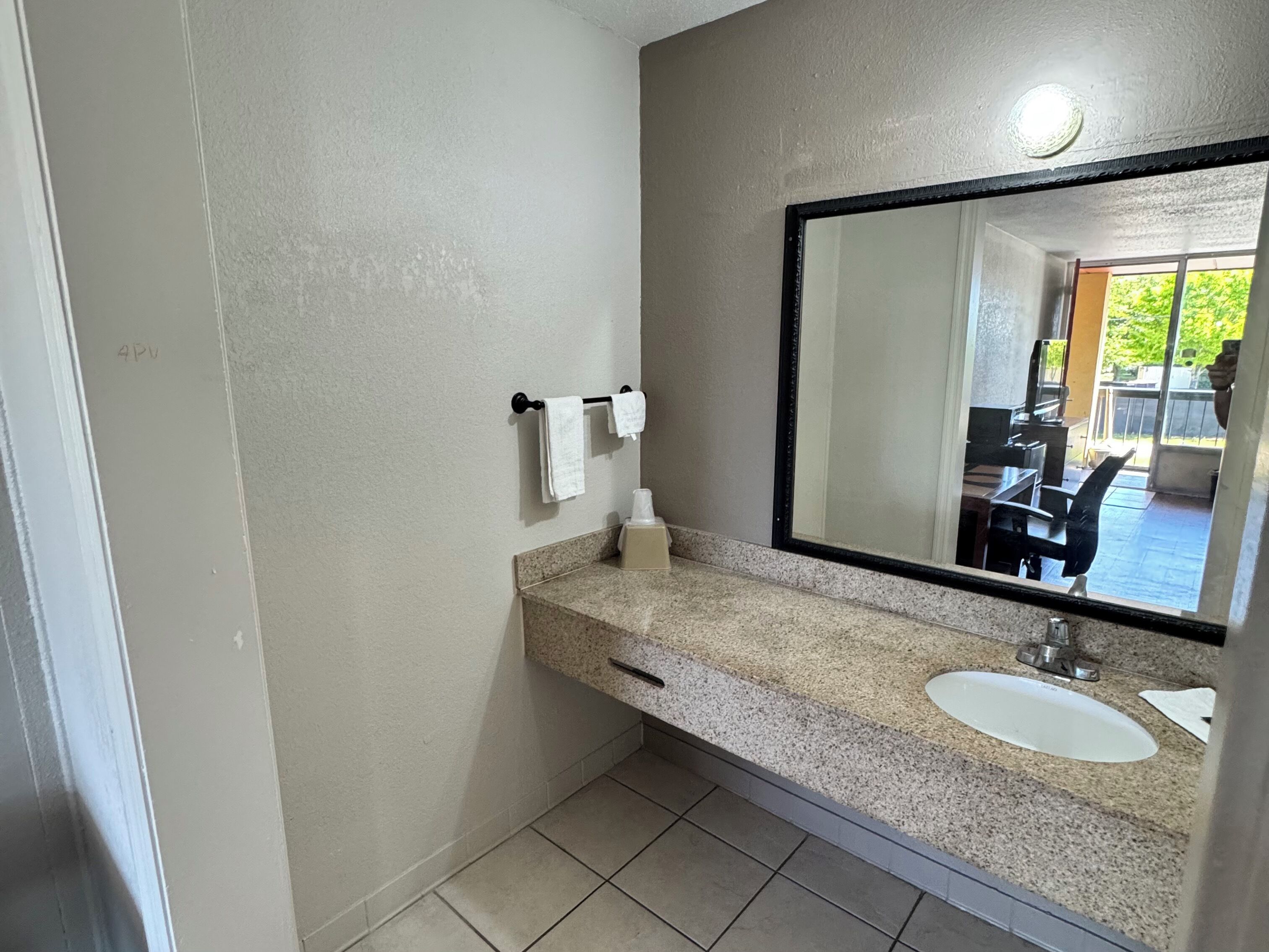 Een badkamer met een granieten aanrecht, twee wastafels, een spiegel en een handdoekhouder.