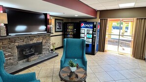 Eine Lobby mit Kamin aus Stein, einem Flachbildfernseher, einer Sitzecke mit einem Türkis-Armlehnstuhl, einem Couchtisch mit Pflanze und einer Pepsi-Getränkeautomaten.