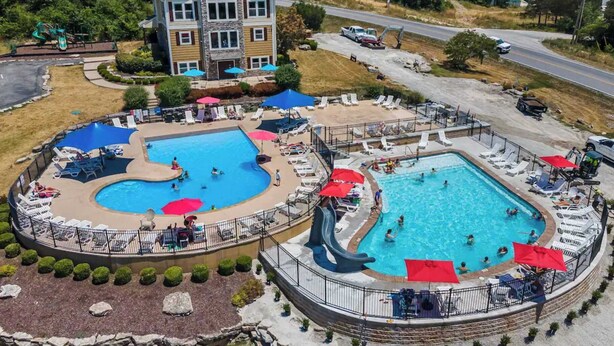 A resort with two swimming pools, a large building, and a road in the background. - Hickory Hideaway w/ Communal Pool Access (Hollister)
