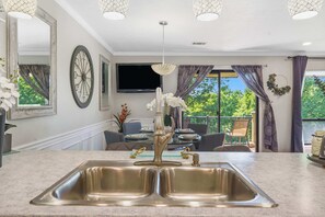 Una cocina moderna con un lavamanos doble, un espejo grande y un comedor con vistas al exterior.