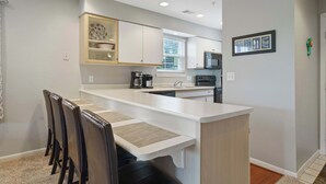 A modern kitchen with white cabinetry, a dining area with a table and chairs, and a small island with a sink.