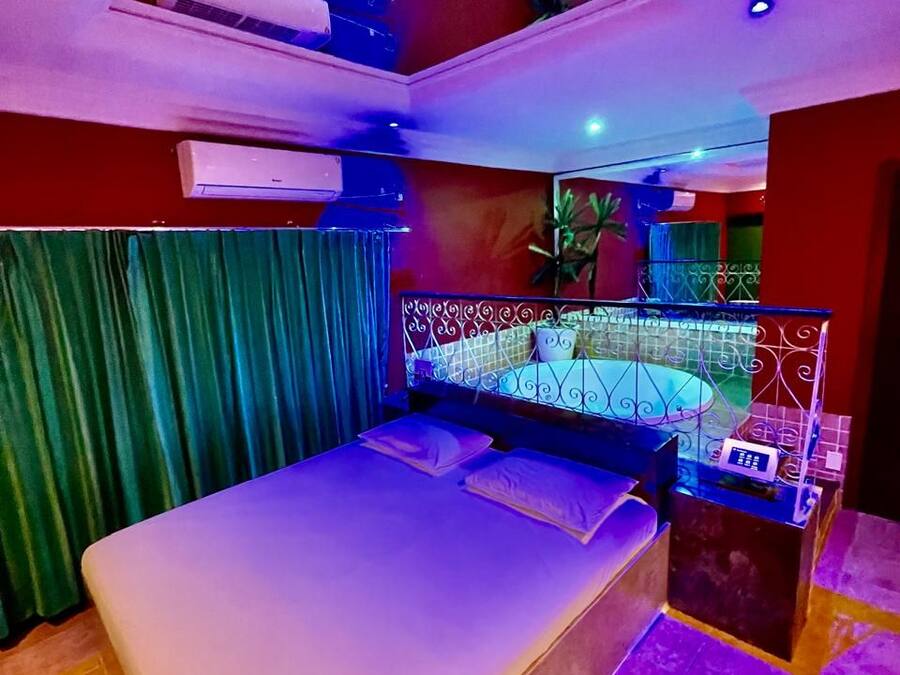 Un dormitorio moderno con cama, aire acondicionado y un pequeño balcón con barandilla.