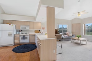Enjoy a comfortable living space with a kitchen area, sofa set, and ceiling fan.