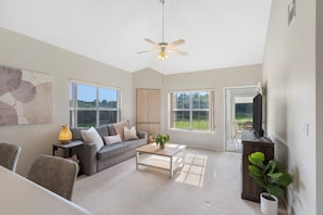 Relax in this spacious living room with a flat-screen TV, comfortable sofa, and potted plant.