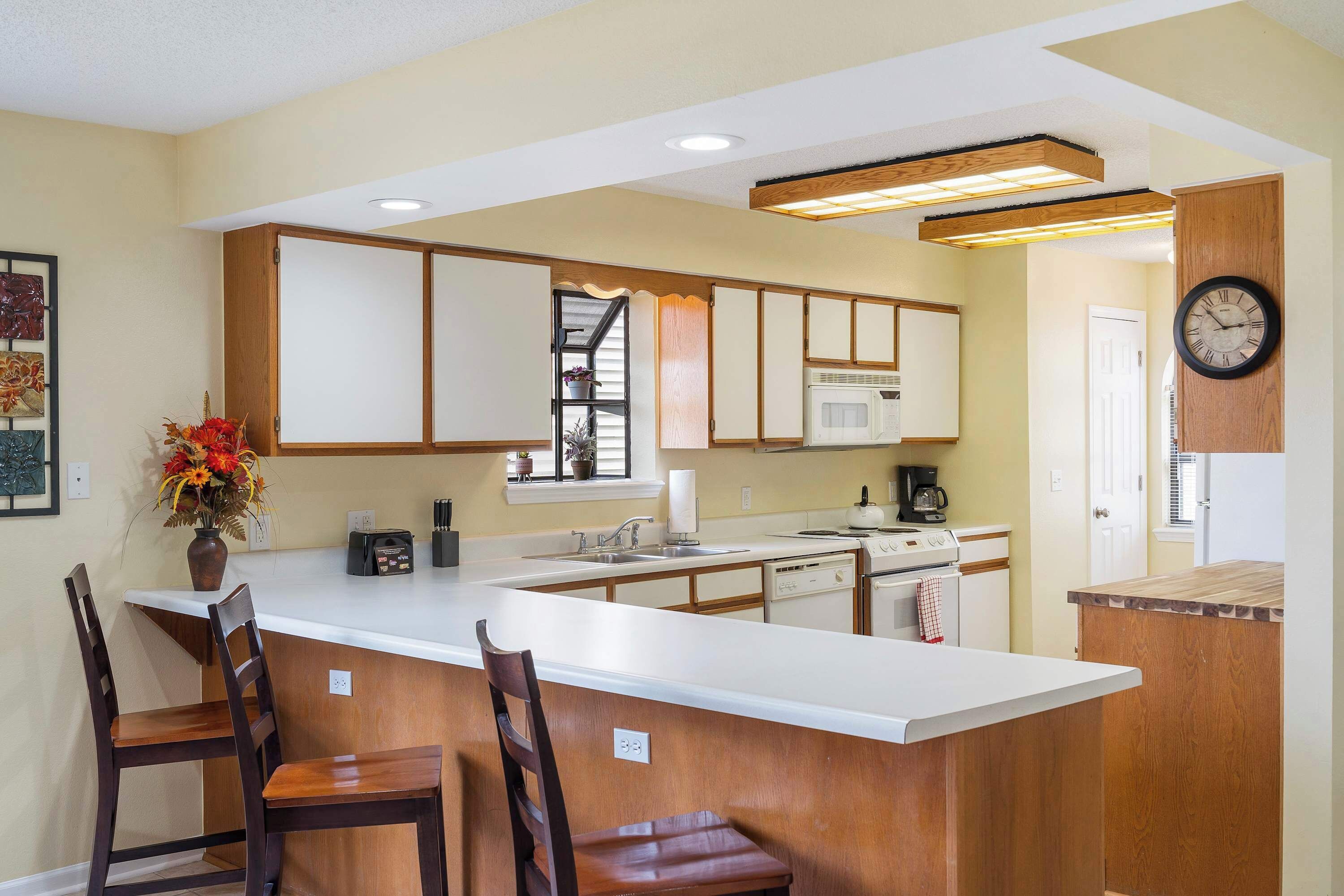 A modern kitchen with a central island, wooden cabinets, and a microwave.