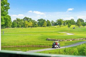 Een golfbaan met een duidelijke route, een vijver en een stenen muur.