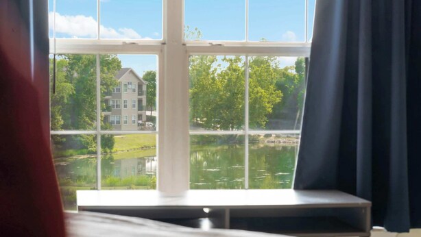 Una habitación con un ventanal grande que da a un lago y un edificio.