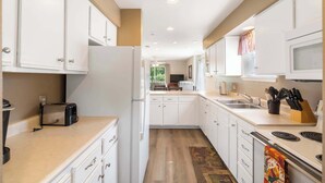 Cocina compacta con armarios blancos, un refrigerador, un microondas, un tostador y un lavamanos.