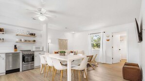 A modern kitchen with white cabinetry, a dining area with a white table and chairs, and a ceiling fan. - Mystic Woods Trio Branson / Pools / Hot Tub (Branson)