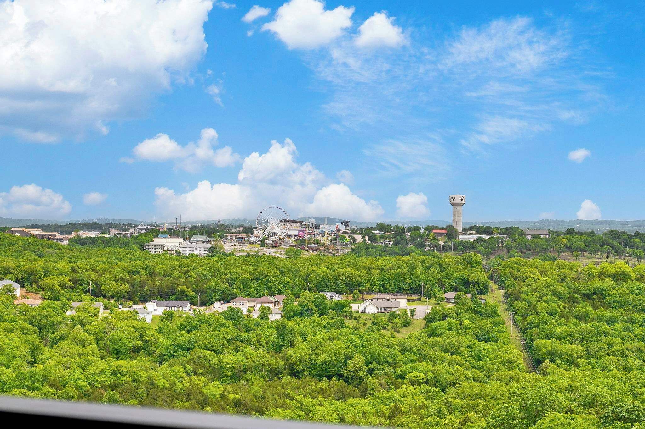 Eine Stadt mit einem markanten Wasserturm, einem großen Riesenrad und einem dichten grünen Wald.