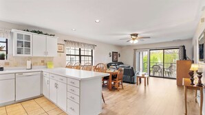 A spacious kitchen with a dining area, a ceiling fan, and a view to a balcony. - The Greens Escape in Branson | Near DT! (Branson)