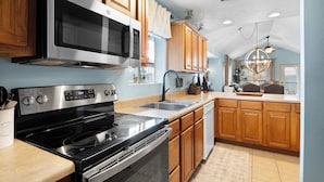A kitchen with wooden cabinets, stainless steel appliances, a double sink, and a chandelier. - Par 7 Penthouse at StoneBridge Resort (Branson West)