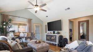 A living room with a ceiling fan, a flat-screen TV, and a large window with blinds. - Par 7 Penthouse at StoneBridge Resort (Branson West)