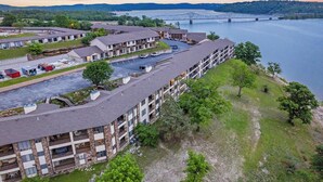A multi-story hotel with balconies, a parking lot, and a view of a bridge over a river. - Lakefront Oasis – Amazing Views! (Kimberling City)
