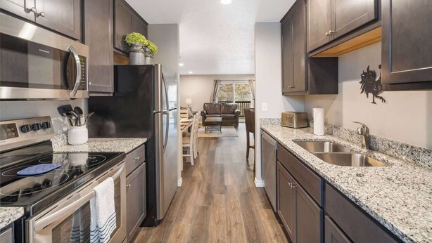 A modern kitchen with dark cabinets, stainless steel appliances, granite countertops, and a central island. - Rockwall Cottage | In the Heart of Branson! (Branson)