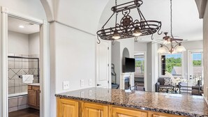 Una cocina con encimera de granito, armarios de madera y una lámpara colgante de estilo campestre.