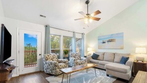A living room with a sofa, two armchairs, a coffee table, a TV, and a ceiling fan. - Retreat by Design | Resort Amenities (Branson West)