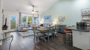 A spacious living area with a dining table, chairs, a sofa, and a kitchen area with a microwave. - Retreat by Design | Resort Amenities (Branson West)