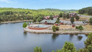A lakeside resort with a swimming pool, guest cabins, and a parking area. - Retreat by Design | Resort Amenities (Branson West)