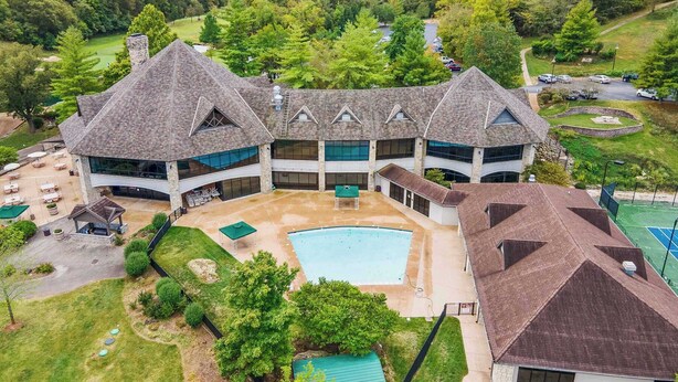 A large, multi-story building with a central courtyard, outdoor pool, and tennis court. - Retreat by Design | Resort Amenities (Branson West)
