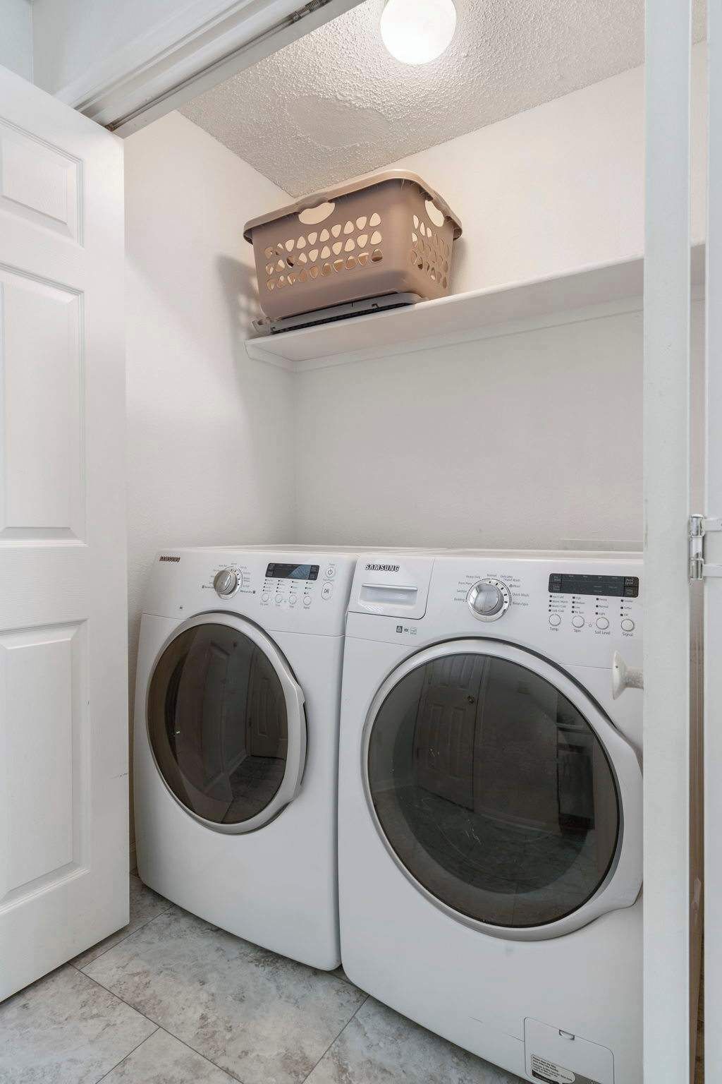 A laundry room with two front-loading washing machines and a shelf above them.