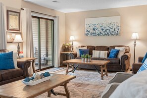 A cozy living room with a brown leather sofa, a wooden coffee table, and a large painting on the wall. - *Newly Updated* Mulligans Escape | Community Pool (Branson)