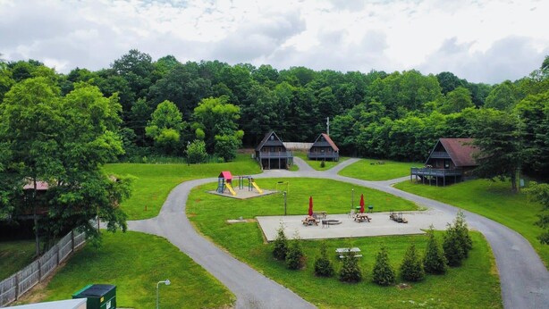 A campground with multiple cabins, a playground, and a picnic area.