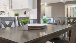 Un comedor con una mesa de madera, dos plantas en macetas y un plato blanco.
