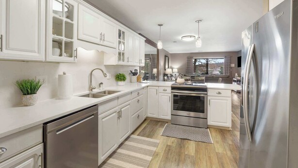 Cocina moderna con armarios blancos, electrodomésticos de acero inoxidable y una isla central.