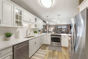 A modern kitchen with white cabinetry, stainless steel appliances, and a central island. - Pool View on Avondale | Walk Out Patio (Branson)