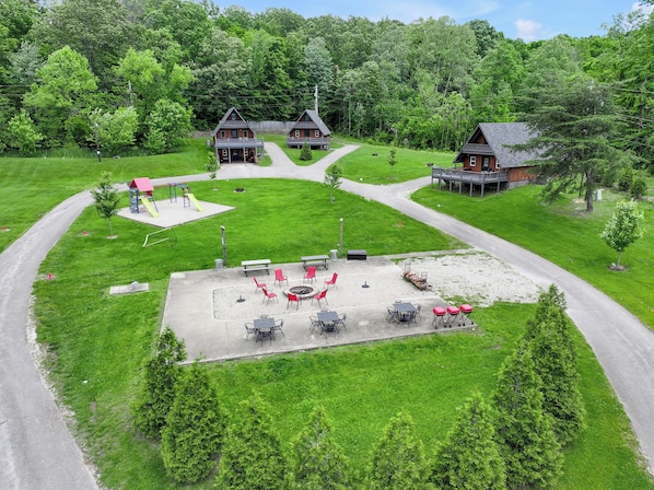 A residential area with two houses, a playground, and a patio area with outdoor seating.
