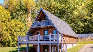 Eine Holzhütte mit Balkon, einer überdachten Terrasse und einer Steinmauer.