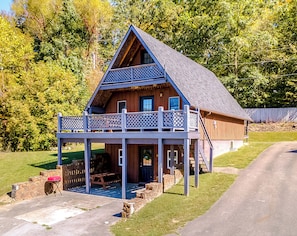 Une cabane en bois dotée d’un balcon, d’une terrasse couverte et d’un mur en pierre.