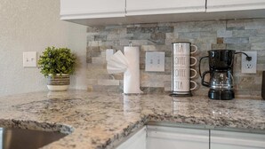 A kitchen counter with a coffee maker, a roll of paper towels, and a potted plant. - The Branson Condo at Fall Creek | Overlooking the Rolling Hills (Branson)