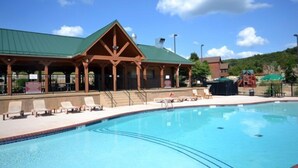A pool area with lounge chairs and a building with a green roof. - Birdie Lane Beauty – Golf, Pools, Gym, & More! (Branson West)
