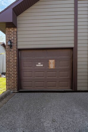 A garage door with a 'No Parking' sign and a warning about towing violators.