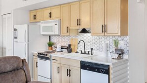 A modern kitchen with wooden cabinets, a white stove, a microwave, and a dishwasher. - Our Landing Place | Access to Pool! (Branson)