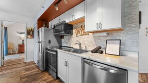 A modern kitchen with stainless steel appliances, white cabinetry, and a wooden ceiling. - On Lake Time Taneycomo - Amazing Views (Branson)