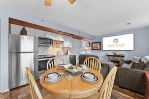 A modern kitchen with stainless steel appliances, a dining area with a wooden table and chairs, and a living room with a fireplace. - On Lake Time Taneycomo - Amazing Views (Branson)