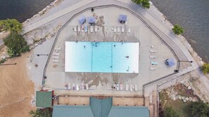 An aerial view of a swimming pool area with multiple lounge chairs and umbrellas. - Whippoorwill Woods – 3 BDR w/ Tons of Amenities! (Branson West)