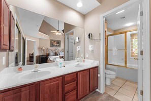 Un baño con tocador doble, un espejo grande y zona de ducha con puerta de cristal.