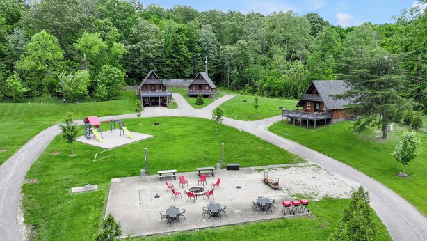 A residential area with two houses, a playground, and a patio area with outdoor seating.