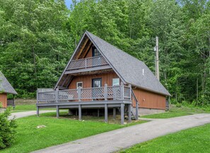 Une cabane en bois dotée d’un balcon, entourée d’arbres.