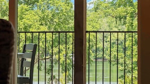 Een balkon met uitzicht op een meer, omringd door bomen.