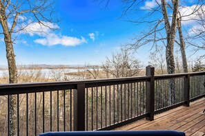 A wooden deck with a view of a lake and trees. - Skipjack Cottage Branson (Branson West)
