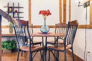 A dining area with a wooden table and chairs, a vase with flowers, and a shelf with decorative items. - Skipjack Cottage Branson (Branson West)