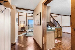 A spacious hallway with wooden floors, a kitchen area with a wooden countertop and cabinets, and a staircase leading to another level. - Skipjack Cottage Branson (Branson West)