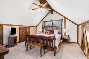 A bedroom with a wooden bed, a TV, a bench, and a ceiling fan. - Skipjack Cottage Branson (Branson West)